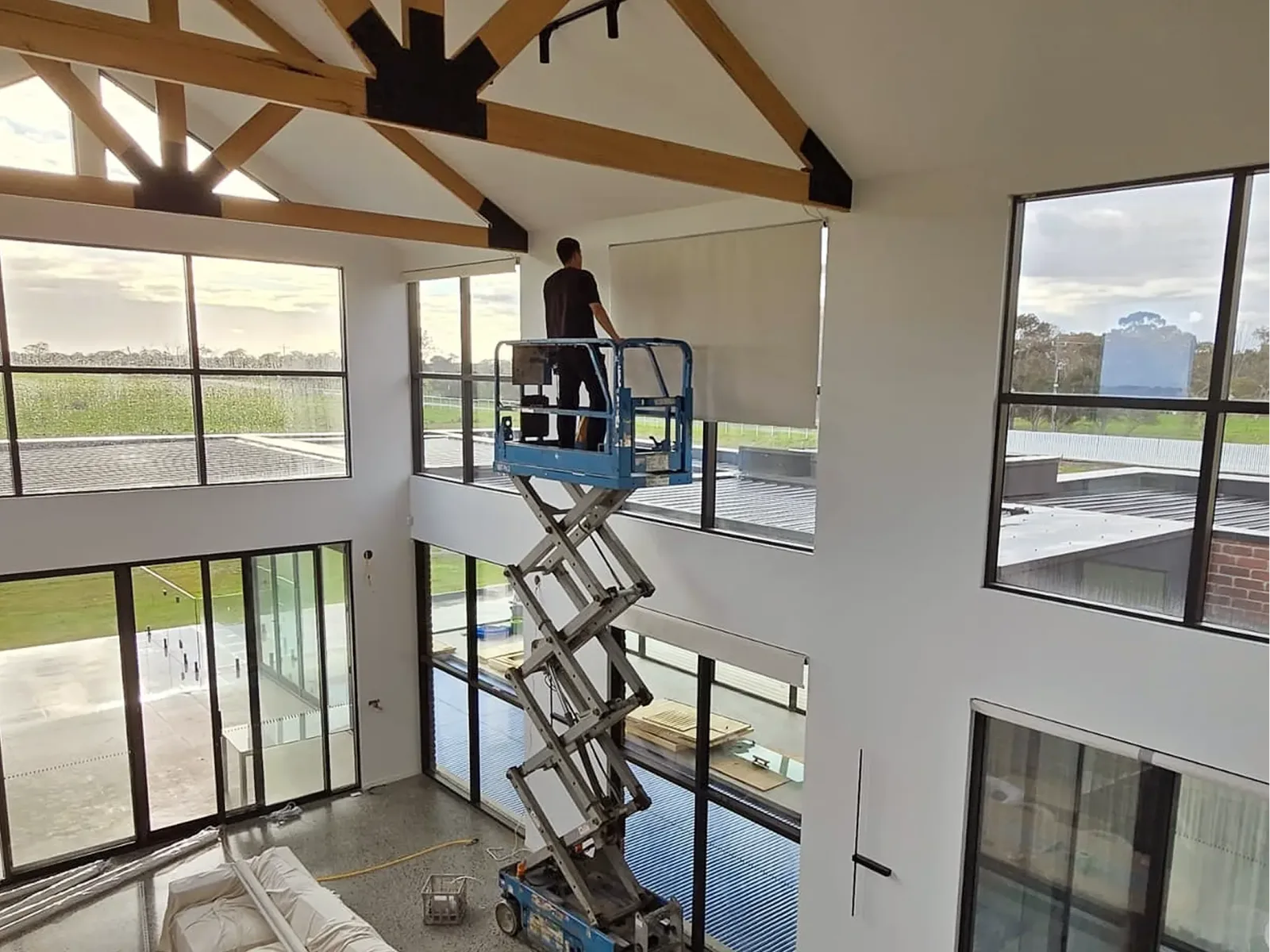 Installer fitting blinds to high windows from a scissor lift
